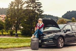 triste mulher sentado em mala de viagem foto