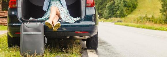 jovem fêmea sentado dentro a tronco do uma carro com malas, mostrando polegar acima sinal, pronto para sair para Férias foto