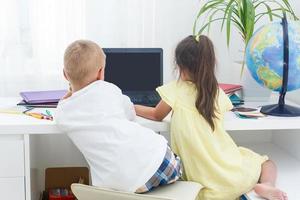 Garoto e menina usando uma computador portátil às escola. foto