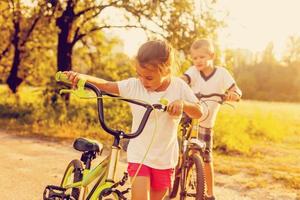 retrato do dois pequeno ciclistas equitação seus bicicletas foto