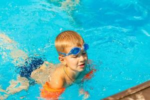 filho engraçado dentro água piscina debaixo Sol luz às verão dia. lazer e natação às feriados. foto