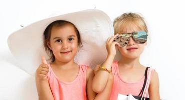 retrato do dois adorável pequeno meninas juntos durante de praia período de férias foto