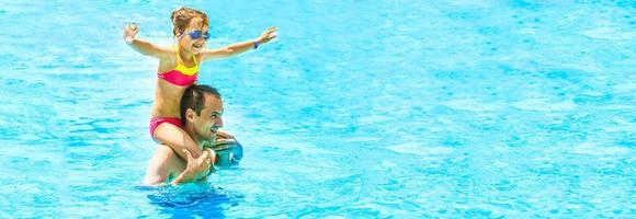 menina e pai feliz se divertindo juntos na piscina ao ar livre foto