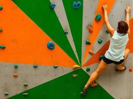 menina escalando uma parede de pedra interior foto