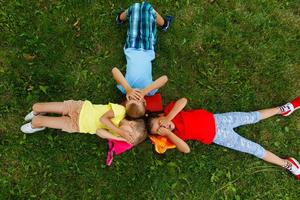feliz crianças deitado em Relva dentro parque foto