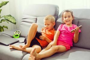 irmão e irmã sentado em sofá às casa usando Móvel telefone. fechar acima surpreso filha e frustrado filho olhando às dispositivo tela. tecnologia Novo geração viciado com aparelhos conceito foto