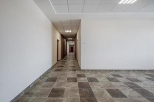 branco esvaziar grandes corredor com vermelho tijolo paredes dentro interior do moderno apartamentos, escritório ou clínica foto