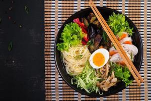 japonês ramen sopa com frango, ovo, shimeji cogumelos e beringelas em Sombrio de madeira fundo. chanko nabe, sumô sopa. topo Visão foto