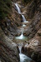 uma desfiladeiro com uma cascata dentro a montanhas foto