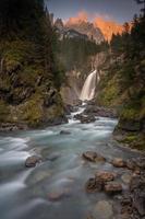 uma grande cascata dentro a vale cercado de montanhas foto