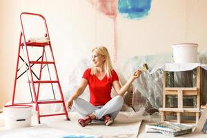 feliz mulher pintura parede às lar. foto