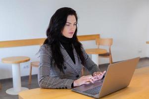 lindo empresária trabalhando em uma computador portátil. fêmea trabalhador autonomo conectando para Internet através da computador. blogueiro ou jornalista escrevendo Novo artigo. foto