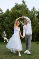 a primeiro dança do a noivo e noiva dentro uma curto Casamento vestir em uma verde Prado foto