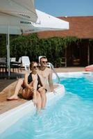 cara e uma menina dentro tomando banho ternos estão relaxante, perto a azul piscina foto