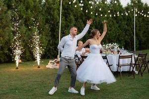 a primeiro dança do a noivo e noiva dentro uma curto Casamento vestir em uma verde Prado foto