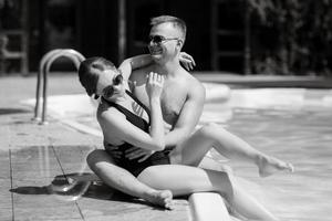 cara e uma menina dentro tomando banho ternos estão relaxante, perto a azul piscina foto