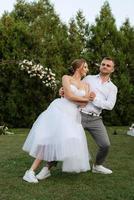 a primeiro dança do a noivo e noiva dentro uma curto Casamento vestir em uma verde Prado foto