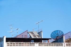 satélite prato e televisão antena em a velho construção com a azul céu fundo dentro a manhã foto