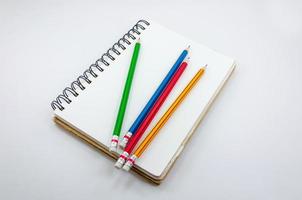 caderno e colorida lápis em branco fundo foto
