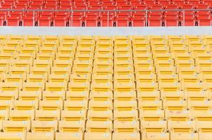 assentos laranja e amarelos vazios no estádio, fileiras de assentos em um estádio de futebol foto