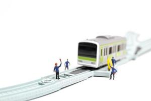 equipe ferroviária em miniatura trabalhando na ferrovia s em um fundo branco foto