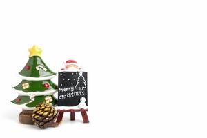 estatueta do papai noel com uma lousa em miniatura com texto de feliz natal em um fundo branco foto