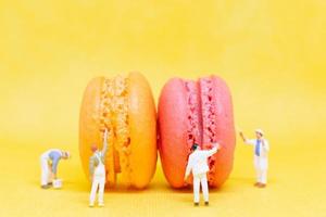 pintores em miniatura colorindo macaroons em um fundo amarelo foto