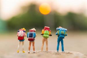 viajantes em miniatura com mochilas caminhando sobre uma rocha, conceito de viagem e aventura
