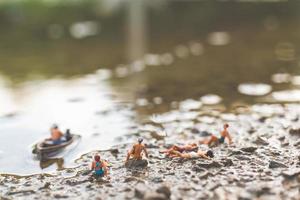 pessoas em miniatura usando maiôs relaxantes na praia, conceito de verão foto