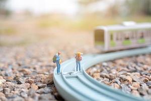 mochileiros em miniatura caminhando em uma ferrovia, conceito de viagens foto