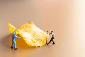 trabalhadores em miniatura trabalhando com batatas fritas foto