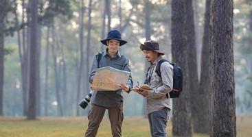 equipe do a ásia naturalista olhando às a mapa enquanto explorando dentro a pinho floresta para levantamento e descobrindo a raro biológico diversidade e ecologista em a campo estude conceito foto