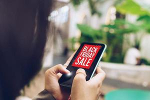 mulher usando um smartphone faz venda on-line na liquidação de sexta-feira negra foto