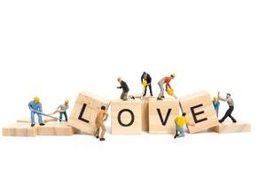 trabalhadores em miniatura construindo a palavra amor em blocos de madeira com um fundo branco, conceito de dia dos namorados foto