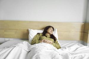 jovem lindo ásia mulher dormindo dentro dela cama e relaxante dentro a manhã foto