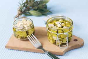 queijo feta marinado em uma jarra de vidro e especiarias contra um fundo azul foto