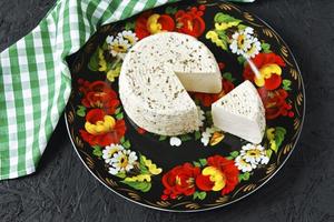 queijo branco em um prato em um fundo preto e guardanapo foto