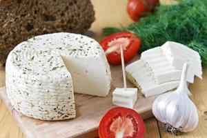 queijo branco, pão, tomate e alho em um fundo de madeira foto