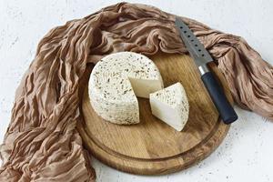 queijo branco em uma placa de madeira em um fundo branco foto
