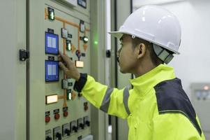 homem engenheiro elétrico verificando a tensão no gabinete de distribuição de energia na sala de controle, manutenção preventiva anualmente, eletricista tailandês trabalhando na empresa