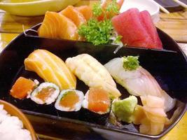 fechar-se e colheita japonês Comida Sushi e sashimi conjunto em Preto golpe e de madeira mesa foto