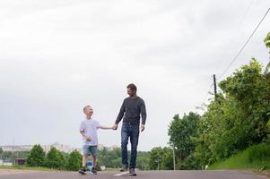 uma pai anda em com dele filho em a estrada. a criança é indulgente foto