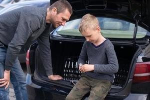 Papai ensina dele fofa filho para usar uma carro reparar ferramenta foto