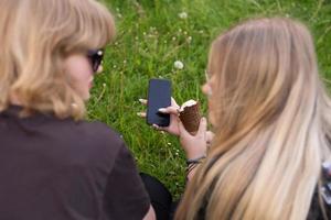 uma Móvel telefone dentro a mãos do uma fofa Adolescência garota. gelo creme em período de férias foto