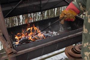 gravetos uma fogo dentro a churrasco, girando sobre queimando carvão foto