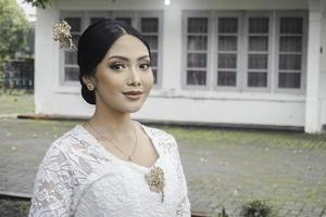 uma jovem indonésio mulher com uma feliz bem sucedido expressão vestindo uma branco kebaya. Kartini's dia conceito. foto