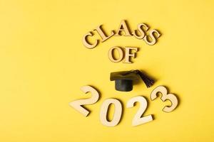 classe 2023 conceito. de madeira número 2023 com graduado boné em amarelo fundo foto