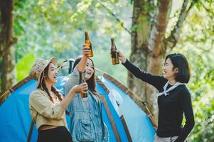 jovem torce e bebe bebida na frente da barraca de acampamento foto