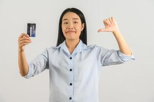 retrato de uma jovem asiática positiva mostrando o salário de bom humor do cartão de crédito isolado no fundo branco foto