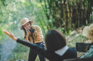 jovem fotógrafo usar digital Câmera fotografia dela amigo em acampamento foto